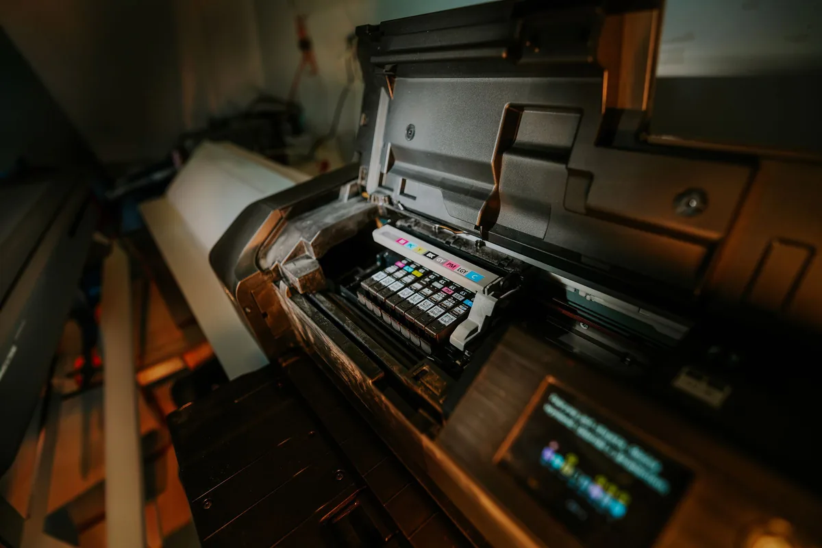 Open wide-format inkjet printer showing its carriage and ink cartridges