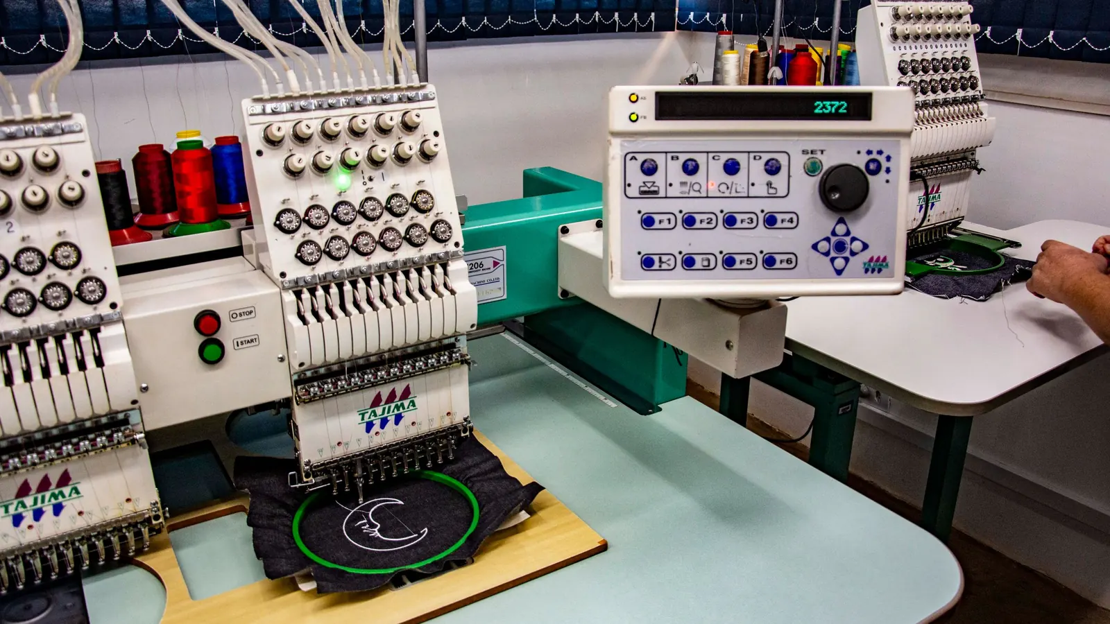 A multi-head embroidery machine stitching a logo onto a garment