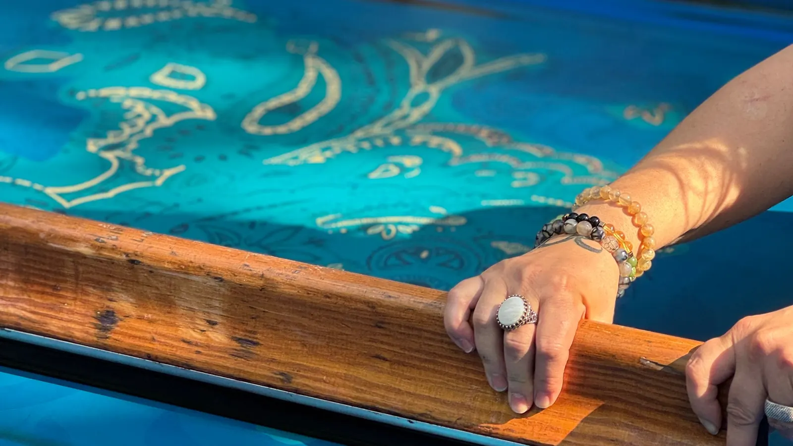 Hands pulling ink across a screen-printing frame onto fabric