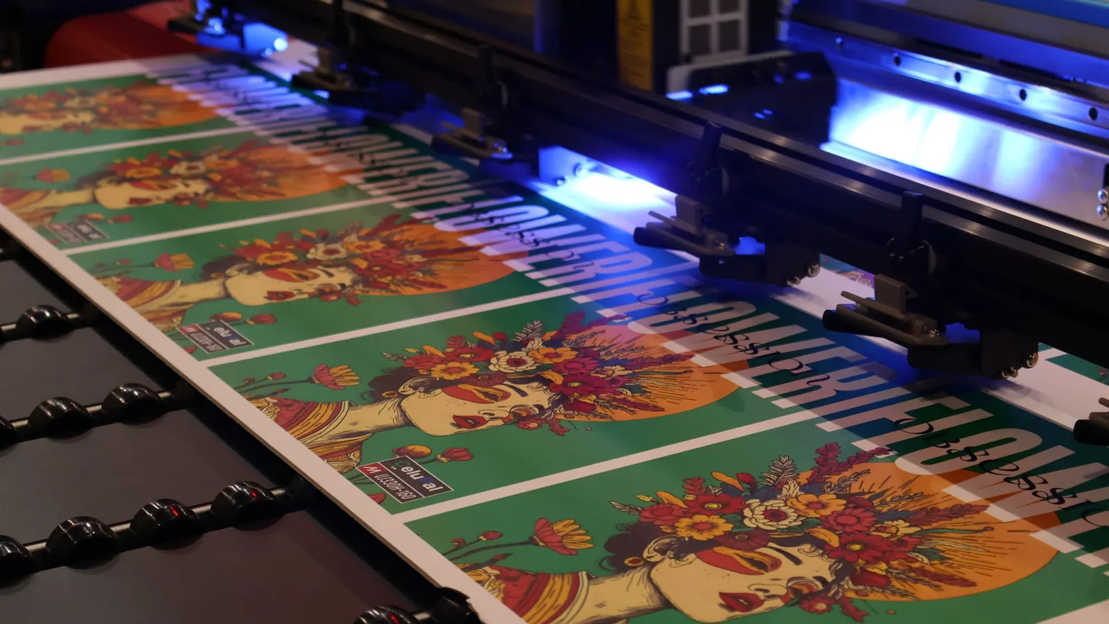 A UV flatbed printer curing a colourful large-format print under its lamp